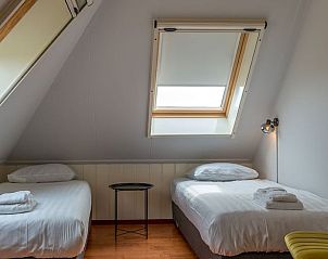 Gemtliches Mansardenzimmer mit zwei Einzelbetten in einem Ferienhaus in Oosterend, Texel, Watteninseln.