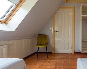 Helles Dachgeschosszimmer in einem Ferienhaus in Oosterend, Texel, mit Dachfenster und bequemen Sitzgelegenheiten.