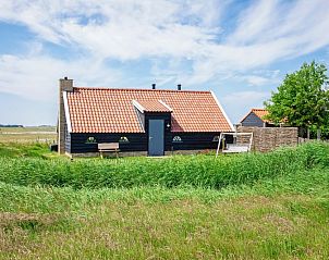 ZoWad - Mhlenhaus Beaufort, Ferienhaus in Oosterend Texel, umgeben von wogendem Gras und blauem Himmel.