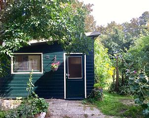De Bemes vakantiehuis in Oosterend Texel met groene gevel en tuin vol bloemen.