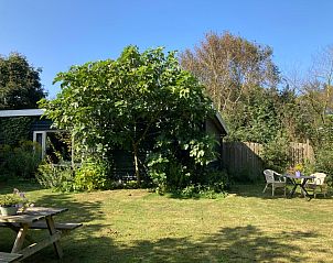 Zonnige tuin met zitjes bij De Bemes vakantiehuis Oosterend Texel omgeven door groen.