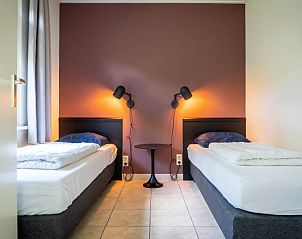 Sfeervolle slaapkamer in Vakantiepark So What, De Koog, Texel. Comfortabele bungalow met tweepersoonsbedden en warme verlichting.