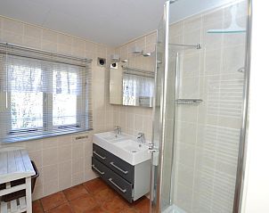 Bathroom in Holiday Home De Nagtegaal 15, Texel with double sink and modern shower.
