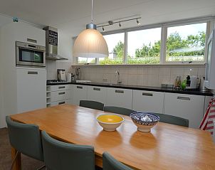 Esszimmer im Ferienhaus de Parel 182 auf Texel, ausgestattet mit groem Tisch und stilvollen Sthlen.