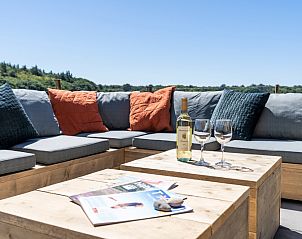 Cozy sitting area on the terrace of Holiday Home 2 in De Dennen, Texel with cushions and wine.