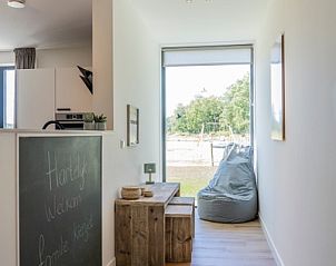 Entrance hall of Holiday Home 2 in De Dennen, Texel with wooden bench and garden view.