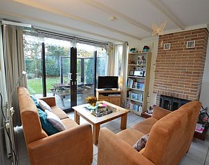 Gemtliches Wohnzimmer im Ferienhaus de Parel 212, De Dennen, Texel mit Blick auf die grne Umgebung.