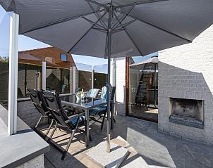 Schaduwrijk terras met parasol bij Vakantiehuis Gortersmient 214, De Dennen, Texel. Geniet van de buitenlucht op de Waddeneilanden.