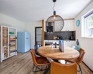 Dining room with wooden table in vacation home de Parel 162, Bungalowpark de Parel, De Dennen, Texel, next to a well-equipped kitchen.