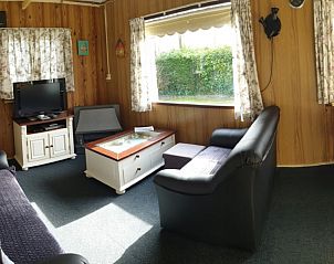 Gezellige leefruimte in De Strandloper bungalow, De Koog, Texel met uitzicht op groen.