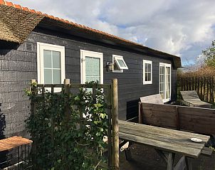 Vacation home at Vakantiepark de Bremakker, De Dennen Texel, with green surroundings and wooden veranda.