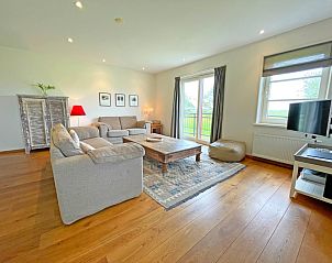 Gezellige woonkamer van Appartement Bos en Duin 40 in De Dennen, Texel met comfortabele banken en uitzicht op de natuur.