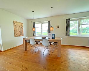 Eetkamer in Appartement Bos en Duin 40, De Dennen, Texel, met grote houten tafel en ramen met uitzicht op de natuur.