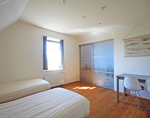 Lichte slaapkamer van Appartement Bos en Duin 40, Texel, met twee eenpersoonsbedden en strandthema.