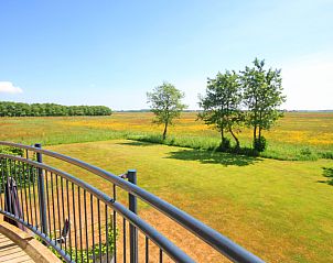 Balkon van Appartement Bos en Duin 40 in De Dennen, Texel, met uitzicht op het weidse landschap en grasvelden.