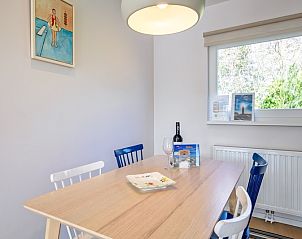 Dining table in Bungalowpark Uterste Coogh - Bungalow 128 - Gerrit, Texel, overlooking the greenery and modern art.