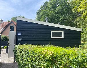 Exterior of vacation home Wollewei in De Dennen, Texel, surrounded by green nature.