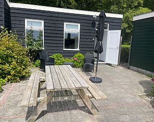 Terrace of Wollewei vacation home in De Dennen, Texel, with wooden picnic table and chairs.