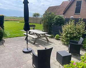 View from the terrace of Wollewei vacation home in De Dennen, Texel, with green garden.