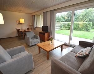 Ruime woonkamer van vakantiehuis Narcis, De Dennen, Texel met eethoek en tuinzicht.