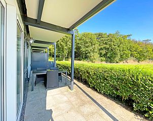 Sunny terrace with seating in Apartment Bos en Duin 12, Texel, surrounded by green nature.