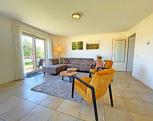 Lichte woonkamer in Appartement Bos en Duin 43 op Texel met comfortabele meubels en toegang tot het balkon.