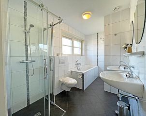 Moderne badkamer in Appartement Bos en Duin 43, Texel met douche, bad en dubbele wastafels.