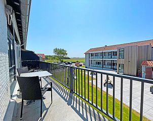 Spacious balcony of Apartment Bos en Duin 28, Texel, with seating and beautiful views of the surroundings.