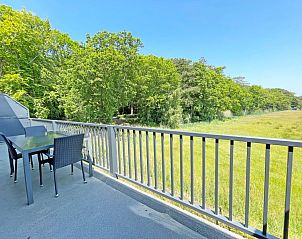 Balcony of Apartment Bos en Duin 31, Texel overlooking green surroundings and space for outdoor dining.