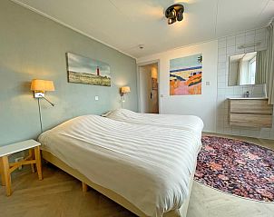 Sfeervolle slaapkamer in Appartement Bos en Duin 26, De Dennen, Texel met tweepersoonsbed en kunst aan de muur.