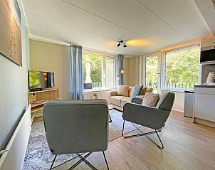 Dining area in Apartment Bos en Duin 22, De Dennen, Texel with wooden table and stylish chairs.