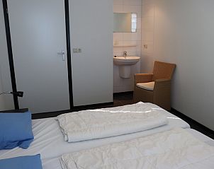 Bedroom in Holiday home Gortersmient 324, De Dennen, Texel with ensuite bathroom and comfortable beds.