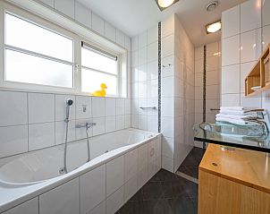 Buitenzijde van Appartement Bos en Duin 37, De Dennen, Texel met charmante architectuur en tuin.