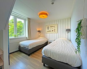 Zweites Schlafzimmer im Appartement Bos en Duin 20, Texel, mit zwei Einzelbetten und Blick auf die grne Umgebung.