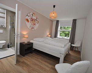 Sfeervolle slaapkamer in Bungalow Verste Coogh 62, De Dennen, Texel met ensuite badkamer.