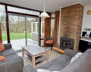 Gezellige woonkamer van Vakantiehuis de Parel 160 in De Dennen, Texel, met uitzicht op de groene omgeving en een knusse open haard.