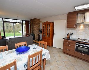 Eetkamer en keuken in Vakantiehuis de Parel 160, De Dennen, Texel, met gezellige sfeer en toegang tot de groene buitenruimte.