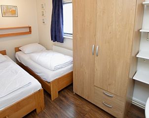 Slaapkamer in Vakantiehuis de Parel 160, Texel, met twee eenpersoonsbedden en praktische opbergruimte voor een comfortabel verblijf.