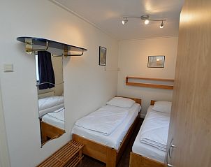 Knusse slaapkamer in Vakantiehuis de Parel 160, De Dennen, Texel, voorzien van comfortabele bedden en warme inrichting.