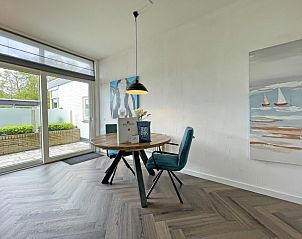 Essecke im Appartement Bos en Duin 03, De Dennen, Texel, mit rundem Tisch und Gartenblick.