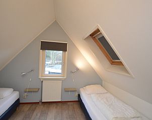 Cozy bedroom with two beds in Holiday home de Parel 214, De Dennen, Texel, perfect for a relaxing stay.