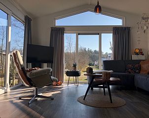 Helles Wohnzimmer im Ferienpark de Bremakker - Bosveld 121, De Dennen, Texel mit groen Fenstern und Blick auf die grne Landschaft.