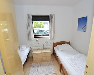 Schlafzimmer mit zwei Betten im Ferienhaus de Parel 286, Texel, mit Blick auf die Natur.