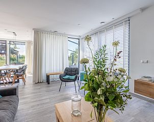 Stylish living room of Strandvilla Hygge, Texel, with flowers and lots of natural light, ideal for relaxation.