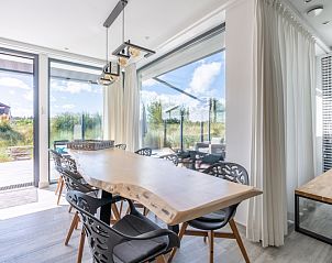 Dining room of Strandvilla Hygge, vacation home Texel, with wooden table and views of the terrace and nature.