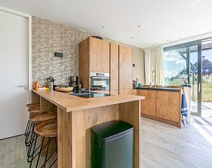 Kitchen of Strandvilla Hygge, De Dennen, Texel, with wooden elements and modern appliances, adjacent to the terrace.