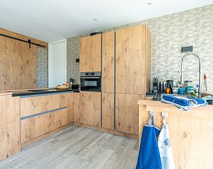 Spacious kitchen of Strandvilla Hygge, Texel, with wood trim and access to outdoor space.