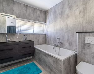 Modern bathroom in Strandvilla Hygge, vacation home Texel, with bathtub and double sink.