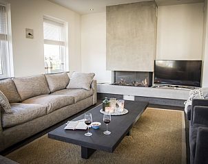 Cozy living room in Villa bij Zee, Bungalowpark 't Hoogelandt, De Dennen, Texel with comfortable sofas and fireplace.