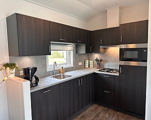 Modern kitchen in Holiday Park de Bremakker - Bosveld 141, Texel with dark wood cabinets and complete equipment.